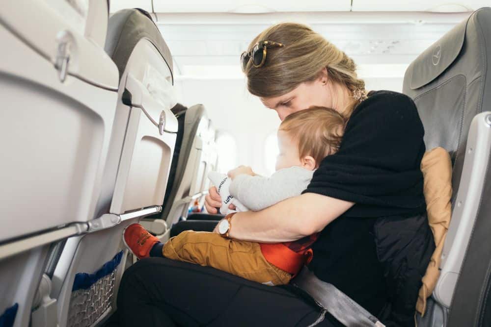 Mother carrying her baby inside an airplane for Passover vacation